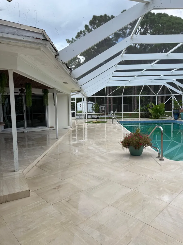 Bright, clean stone pool deck with a potted plant beside the pool