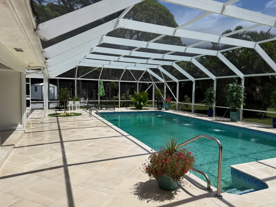 Clean travertine pool deck and pool under a screen enclosure