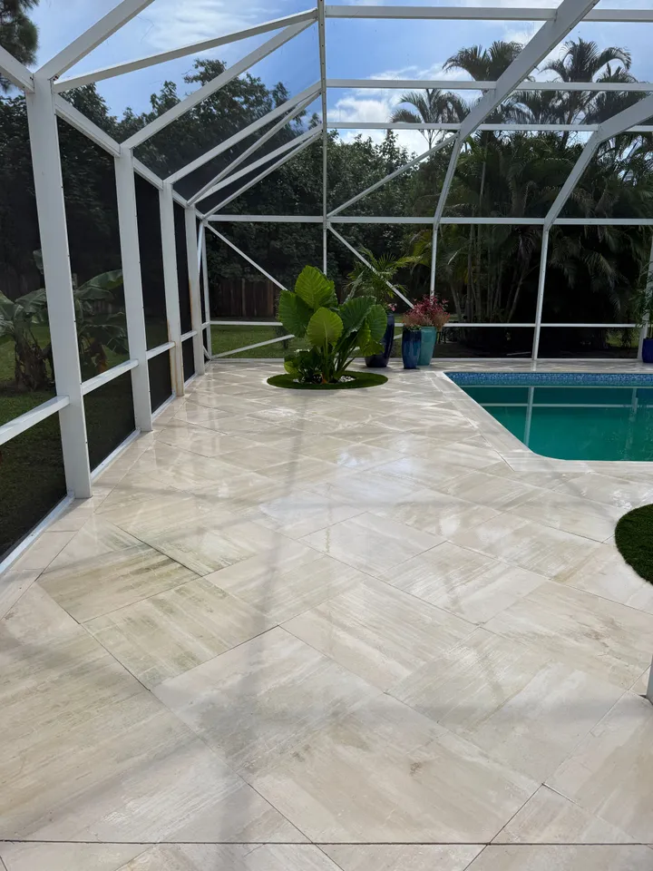Clean stone pool deck and lap pool under a screen enclosure