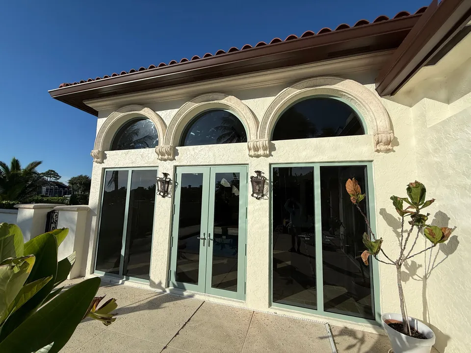Clean glass patio doors beneath arched transoms on a Mediterranean-style home