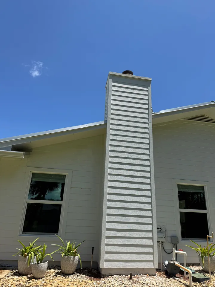 Clean white chimney and siding under a blue sky