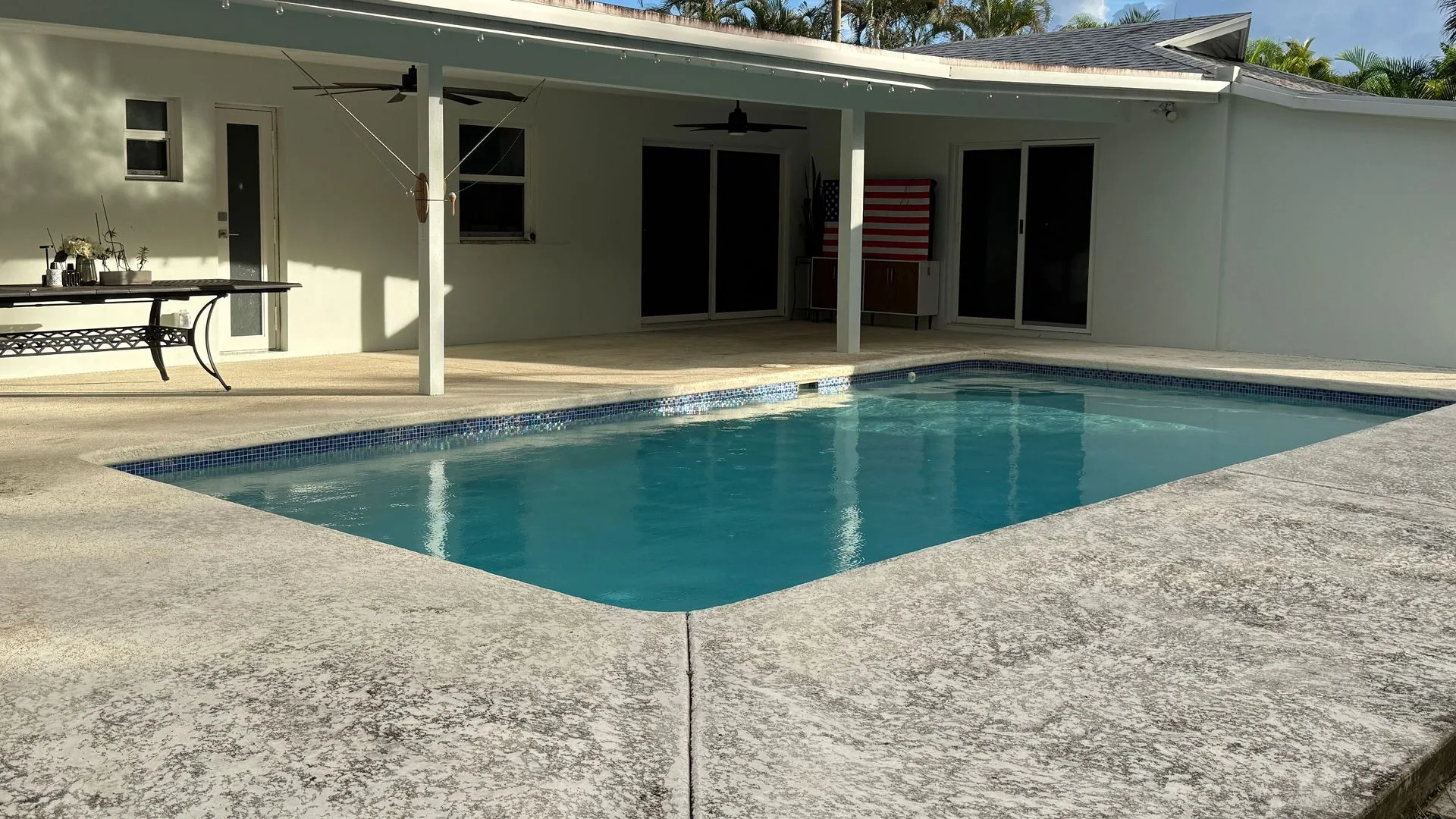 Before: concrete pool deck grey with dirt and mildew behind a white home