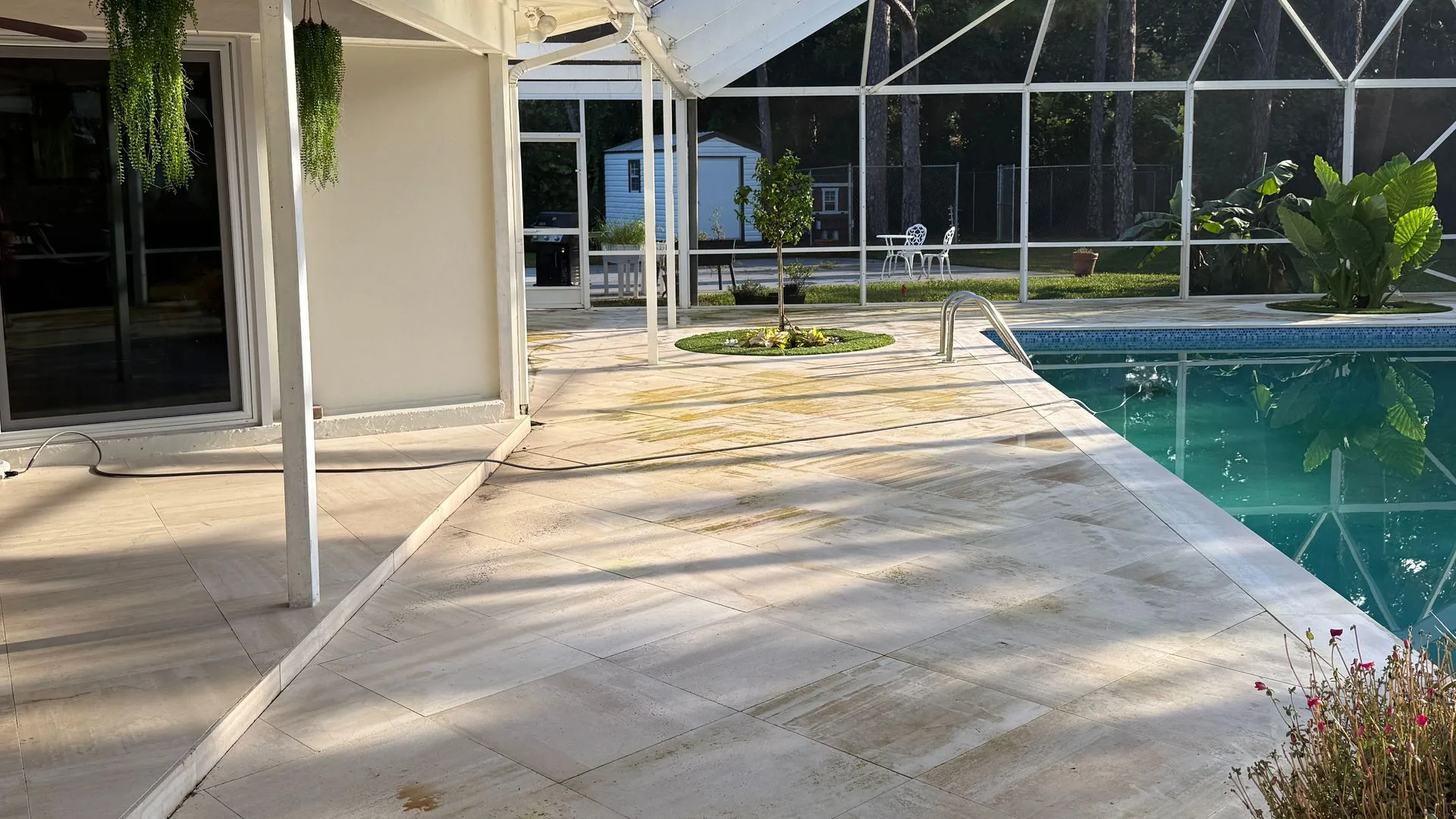 Before: travertine pool deck streaked with algae and dirt under a screen enclosure