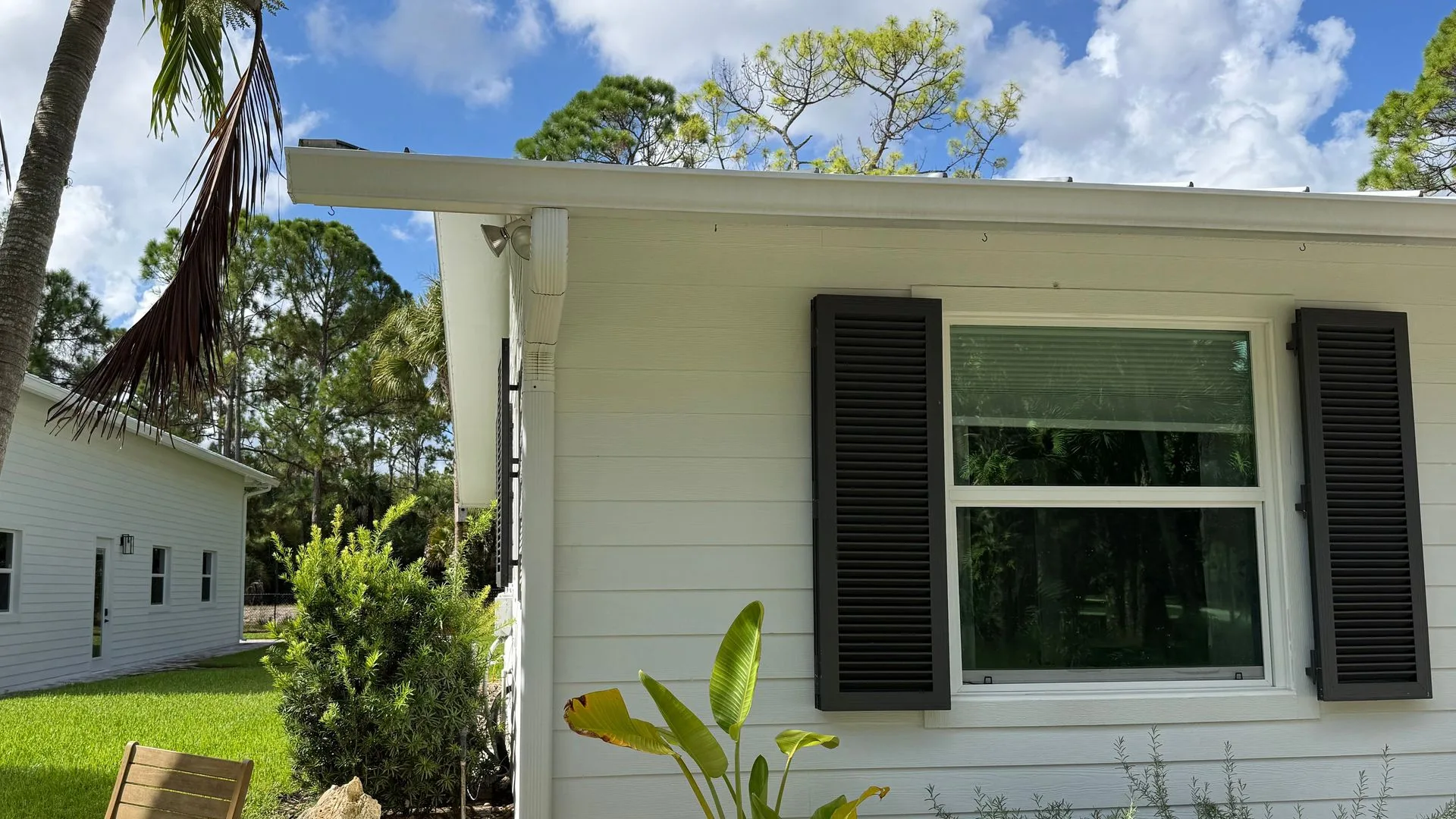 After: crisp white siding and black shutters under a blue sky