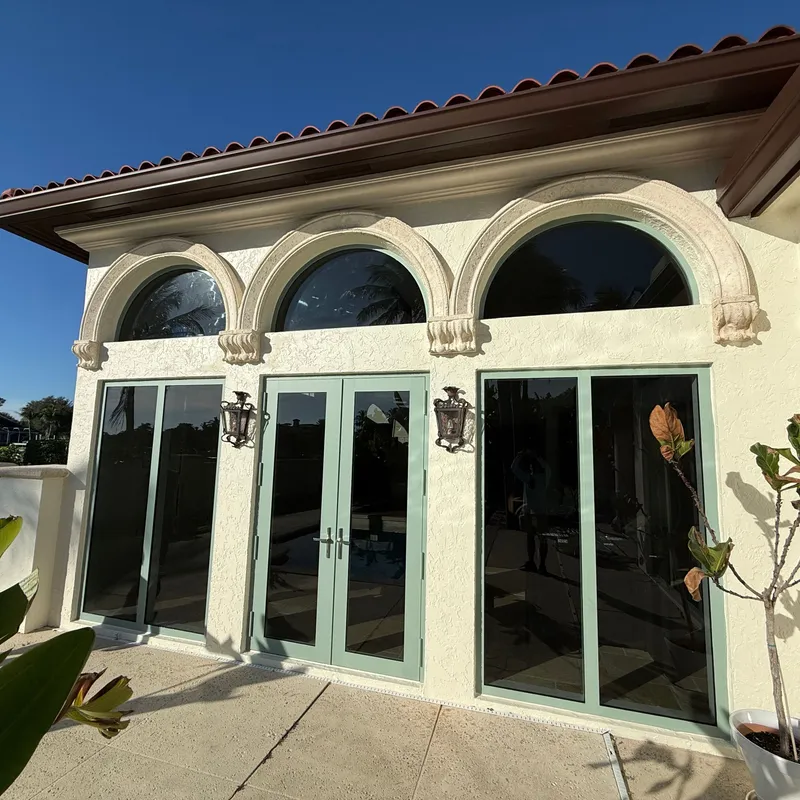 Clean glass patio doors and arched transoms beside a courtyard